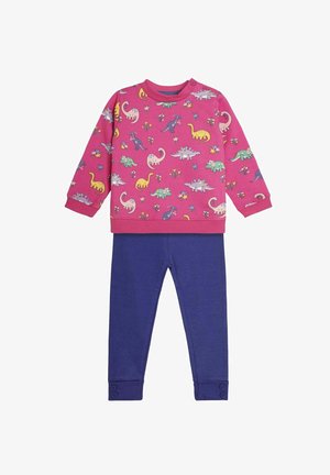 Różowa bluza z kolorowym nadrukiem dinozaura, w połączeniu z niebieskimi, prążkowanymi legginsami z guzikami przy mankietach.