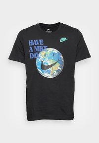 Svart bomullströja med texten "HA EN NIKE-DAG" i blått, en leende jordgrafik och en grön Nike-logotyp på axeln.