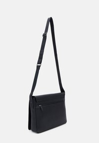 Borsa a tracolla nera in pelle con tracolla regolabile, texture liscia, tasca frontale con zip e design strutturato. Misura circa una dimensione media.