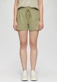 Lichtolijfgroene shorts gemaakt van een zachte stof, met een elastische tailleband met koord en zijzakken. Eenvoudig ontwerp, zonder patronen.