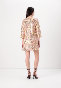 Abito floreale in paillettes con maniche a tre quarti, motivi di fiori rosa e gialli, una cerniera sul retro e una vestibilità morbida, abbinato a sandali neri con tacco.