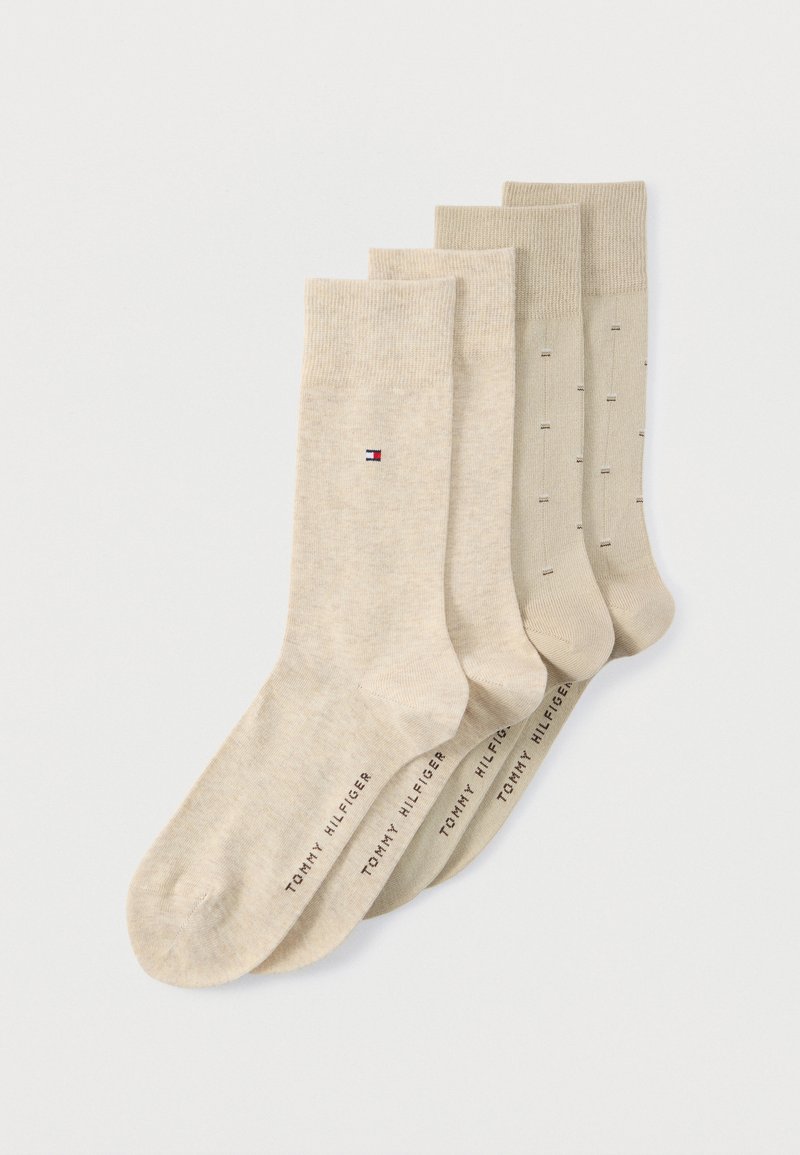 Τέσσερα ζευγάρια μπεζ κάλτσες Tommy Hilfiger τοποθετημένα σε σειρά, με το λογότυπο κοντά στην κορυφή και το όνομα της μάρκας στα δάχτυλα των ποδιών.