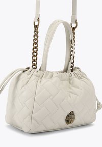 Borsa a tracolla bianca trapuntata con parte superiore arricciata, dotata di tracolla a catena intrecciata, lacci in pelle e un emblema decorativo dorato sul davanti.