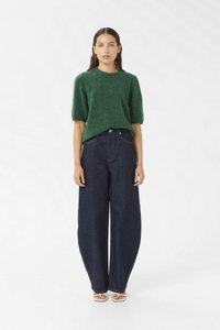 Green, textured knit sweater with short sleeves paired with high-waisted, wide-leg dark denim jeans and light-colored sandals.