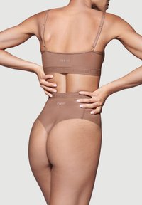 Brown seamless bralette en hoge taille broek, met een gestructureerde tailleband met het 'ITEM m6' logo, gladde stof en verstelbare banden.