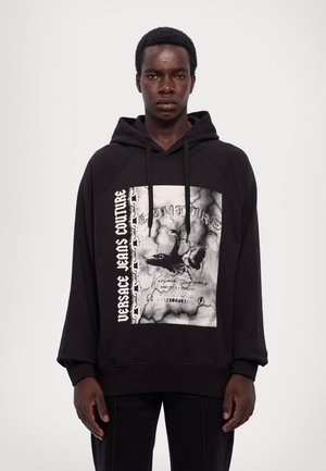 Felpa nera con cappuccio con una grafica frontale caratterizzata da un design invecchiato, testo bianco e motivo a catena, completata da un cordino e maniche raglan.
