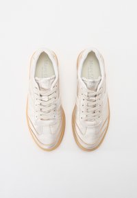 Lysebeige sneakers med en tekstureret overflade, der har snørelukning, rundet tå og sål af gummigummi. Mærkning på tungen.