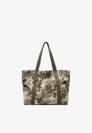 Kangasostoskassi, jossa on vihreä ja beige kukkakuvioinen maastokuvio ja useita metallisia silmukoita, sekä kaksi pitkää kangaskahvaa.