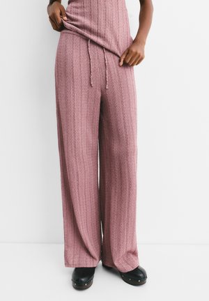 Pantaloni a gamba larga in tessuto rosa testurizzato con righe verticali. Presentano una vita con cordino e si abbinano a calzature nere.