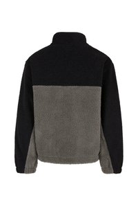 Fleece tipo džemperis su aukšta apykakle, spalvotomis blokinėmis juostomis juodos ir pilkos spalvos, ir tekstūruota, švelni paviršius.