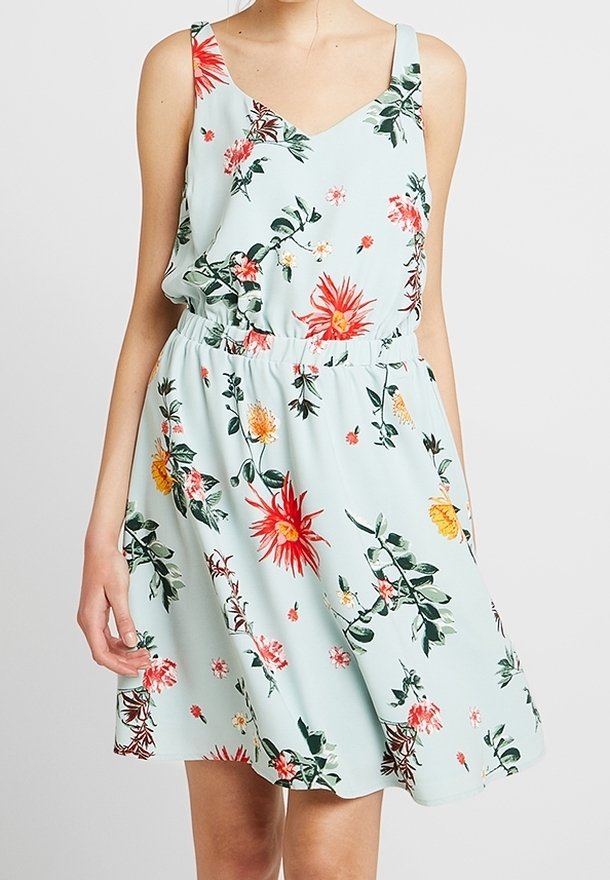 Blommig klänning i ljus mintgrön tyg med V-ringning, justerbara axelband och elastisk midja. Den har livfulla röda och gula blommor.