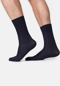 Calcetines de tobillo en azul marino oscuro con un puño acanalado. Textura suave, material ligero y ajuste estándar. Sin patrones ni acentos visibles.