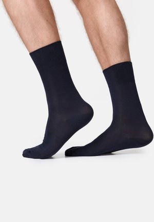 Mørk navy ankelstrømper med ribbet kant. Glat overflade, let materiale og standard pasform. Ingen synlige mønstre eller detaljer.