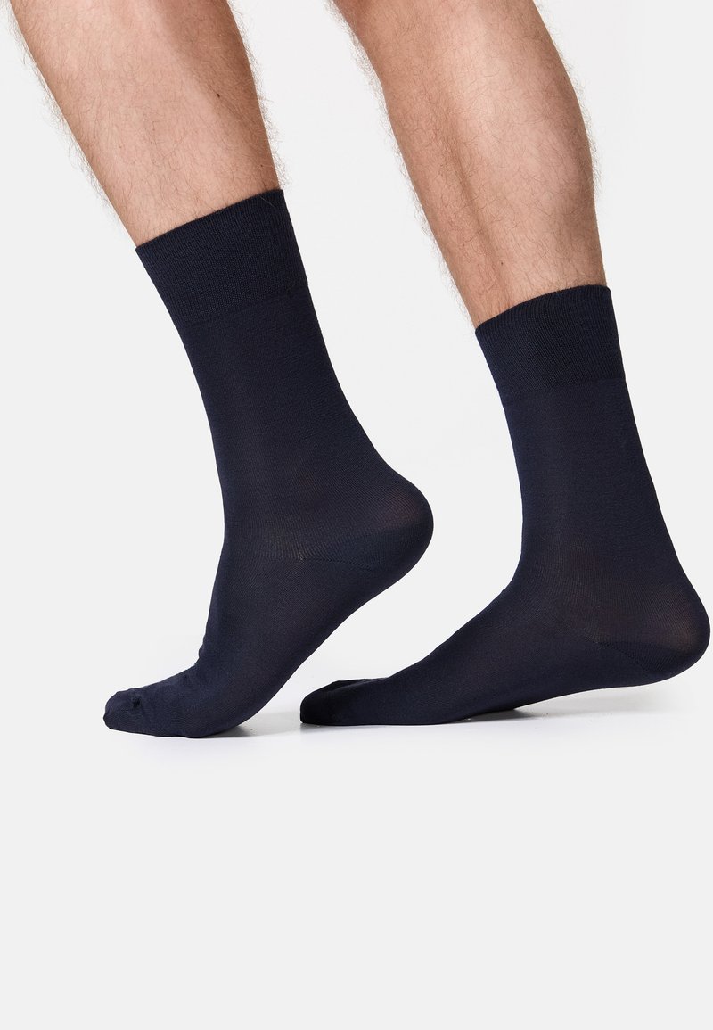 Calzini alla caviglia di un blu scuro navy con bordo a costine. Texture liscia, materiale leggero e vestibilità standard. Senza motivi o dettagli visibili.