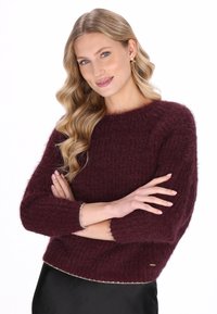 Bordeaux, geknipte gebreide trui met een gestructureerde afwerking, brede mouwen en een contrasterende afwerking bij de manchet en zoom. Zacht, gezellig uiterlijk.