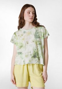 Camiseta de manga corta en tejido suave y ligero con un patrón de acuarela en verde y blanco, combinada con pantalones cortos amarillos claros.