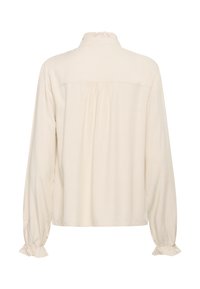 Blouse à manches longues couleur crème avec col montant froncé et poignets froncés élastiqués, vue de dos.