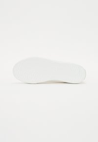 Semelle de sneaker en caoutchouc blanc avec un motif ondulé texturé, des bords arrondis et un branding subtil. Fini lisse avec un profil plat.