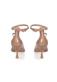 Huidkleurige patenten leren hakken met een enkelbandje, spitse neus en een slanke, schuine hak. Gladde textuur en goudkleurige gespdetails.