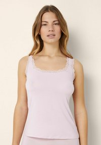 Helles rosa Camisole mit Spitzenbesatz entlang des Ausschnitts und der Träger. Weicher, glatter Stoff. Schlichtes, figurbetontes Design. Keine Muster oder Verzierungen.