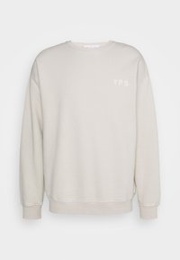 Beige mikina s kulatým výstřihem, dlouhými rukávy, manžetami a malým logem "YPS" na hrudi. Vyrobena z měkké, texturované látky.