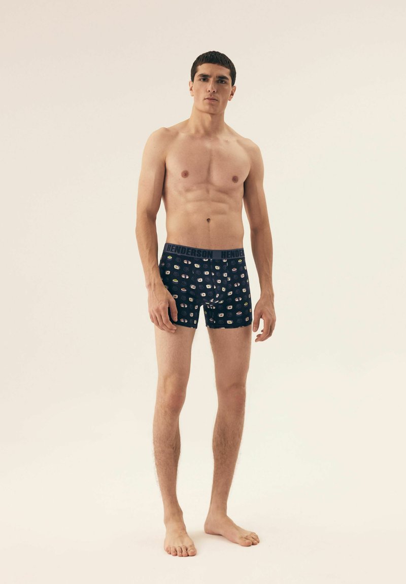 Bokserki w granatowym kolorze z wzorzystym wzorem, wyposażone w wygodny elastyczny pasek z napisem "HENDERSON". Teksturowana powierzchnia.