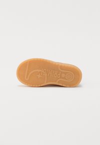 Rubber shoe sole with a textured, herringbone pattern and a logo print. Color is light brown with an even finish and minimal detailing.