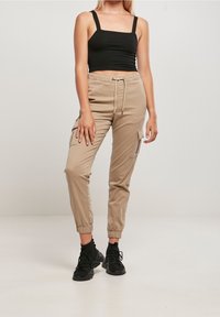 Khaki cargo kalhoty s elastickým páskem a manžetami, boční kapsy, spárovány s černým zkráceným topem a černými teniskami.