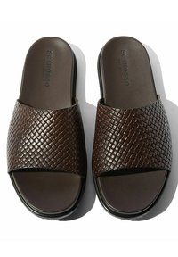 Bruine geweven lederen sandalen met een platte zool en open teen. Voorzien van een gestructureerde bovenband met een gladde binnenvoering. Hardware minimaal.