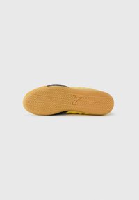 Suela de zapatilla con un patrón de banda de rodadura detallado y el logotipo de Puma en el centro, mostrado contra un fondo blanco liso.
