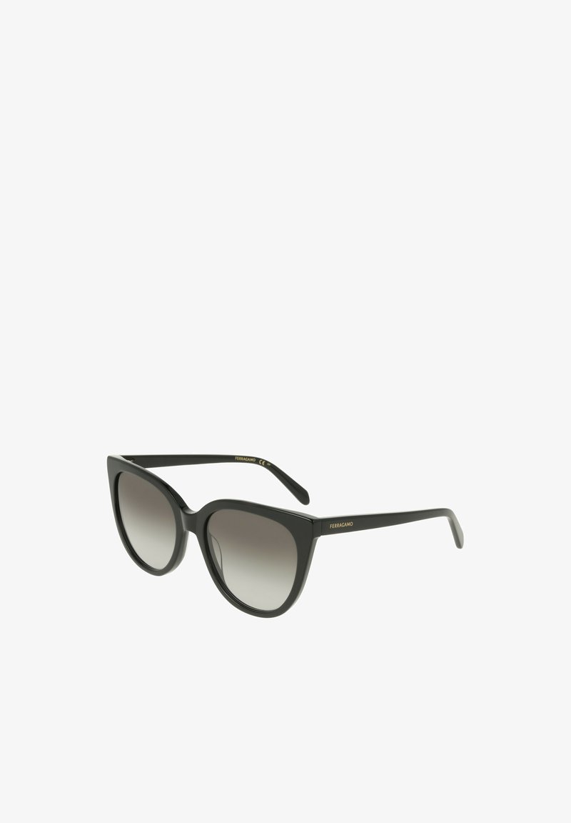 Lunettes de soleil noires style œil de chat avec des verres dégradés, finition mate et branding doré « Ferragamo » sur les branches. Texture lisse et forme audacieuse.