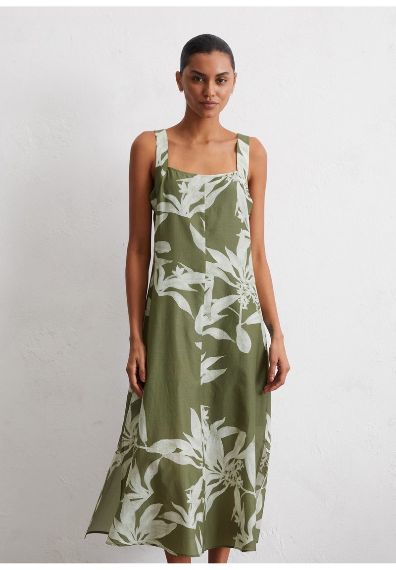 Grünes Leinenkleid mit weißem botanischen Druck, quadratischem Ausschnitt und breiten Trägern. A-linienförmiger Schnitt mit Länge bis zur Mitte der Wade. Leichter Stoff.