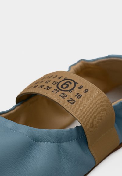 Μαλακό μπλε δερμάτινο παπούτσι με ταμπά ελαστικό λουράκι που φέρει εκτυπωμένους αριθμούς και τον αριθμό 6 σε κύκλο στο λουράκι.