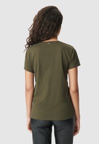 Olijfgroen t-shirt met korte mouwen en een ronde halslijn, voorzien van een soepele textuur en een klein merkembleem op de achterkant, gedragen met zwarte broek.
