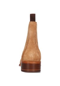 Botín de ante en color marrón claro con punta redonda y un tacón de madera de altura media. Presenta una lengüeta de tela acanalada para facilitar su puesta.