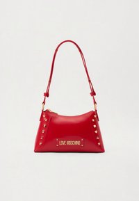 Red leather handbag with a curved shape, gold hardware, and pyramid studs on the sides. Features a gold logo plate at the front.