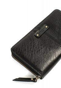 Zwarte leren portemonnee met een gestructureerde afwerking, een ritssluiting en een klein leren label met gouden accenten. Compact en rechthoekig ontwerp.