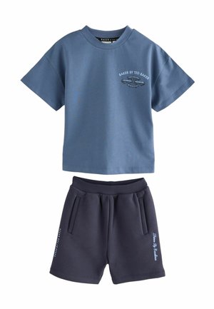 T-shirt bleu clair à manches courtes avec logo sur le devant, associé à un short bleu marine doté de poches latérales et de texte sur la jambe. Tissu en mélange de coton.