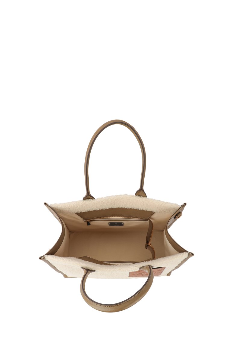 Beige Einkaufstasche mit einem flauschigen cremefarbenen Innenraum, ausgestattet mit braunen Ledergriffen und einer Reißverschlusstasche. Glatte Außenfläche mit einer weichen Textur.