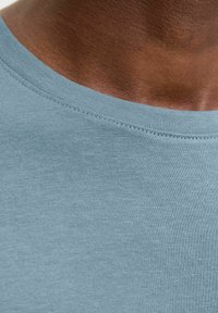 Light blue cotton t-shirt with a round neckline, featuring fine ribbed stitching along the collar and a smooth texture.