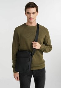 Czarna skórzana torba na ramię z regulowanym paskiem, posiadająca przednią kieszeń na zamek, gładką teksturę i minimalistyczny design.