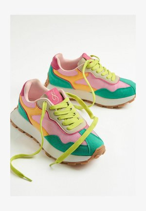 Helle Turnschuhe mit pinkem, gelbem und grünem Mesh, einer stabilen weißen Sohle und einer braunen Gummisohle. Grüne Schnürsenkel und Logo-Akzent.