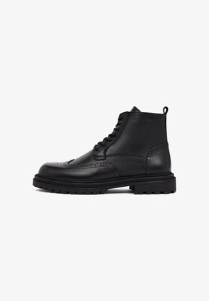 Bottines en cuir noir avec une finition texturée, présentant des détails brogue et une semelle en caoutchouc robuste pour une meilleure adhérence. Design à lacets.
