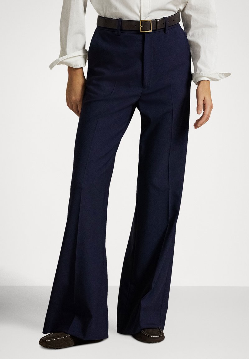 Calças de perna larga cor azul-marinho feitas de tecido liso, com cintura alta, pregas frontais e um cinto castanho com fivela quadrada dourada.