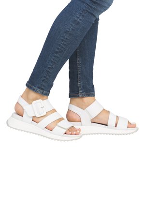 White sandals with multiple straps, buckle detail, and a ridged sole. Designed for comfort with open back and toes exposed.