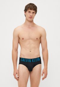 Calvin Klein férfi fekete alsónadrág sima felülettel, széles derékpánttal, merész kék logóval és szoros illeszkedéssel.