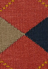 Tkanina z wzorem diamentowym w kolorze pomarańczowym, beżowym i granatowym, z widocznym żółtym szyciem, co tworzy teksturową powierzchnię.