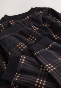 Fleece-sweater i marineblå med rutet mønster i brun og creme, med ribstrikkede manchetter og halsudskæring. Blød tekstur, lagt fladt.