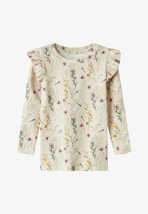 Chemise beige à manches longues avec des détails à volants aux épaules, décorée de fleurs sauvages roses et jaunes et de petites illustrations de libellules.