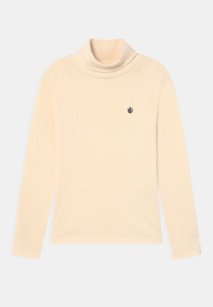 Maglietta a maniche lunghe color crema con collo a dolcevita e piccolo logo di una barca a vela nera sul petto a sinistra.